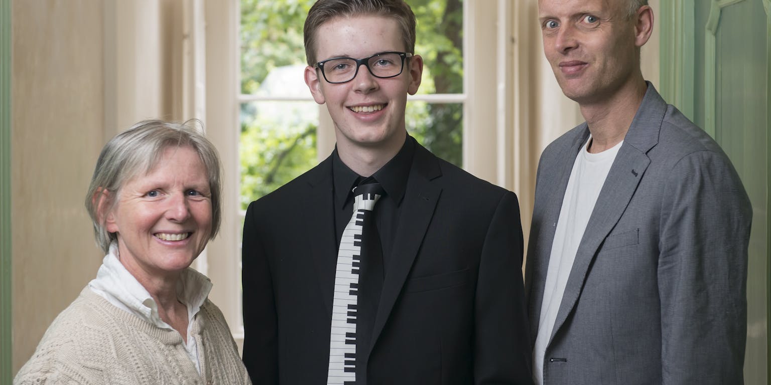 Tim Povel met zijn docenten poseren voor een deur.