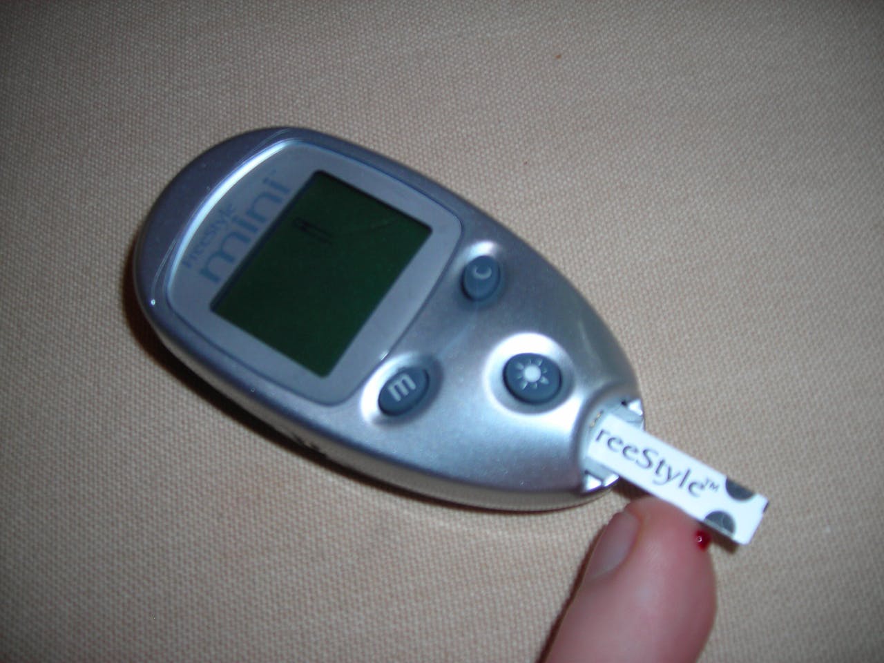 Een persoon die een digitale glucosemeter vasthoudt.