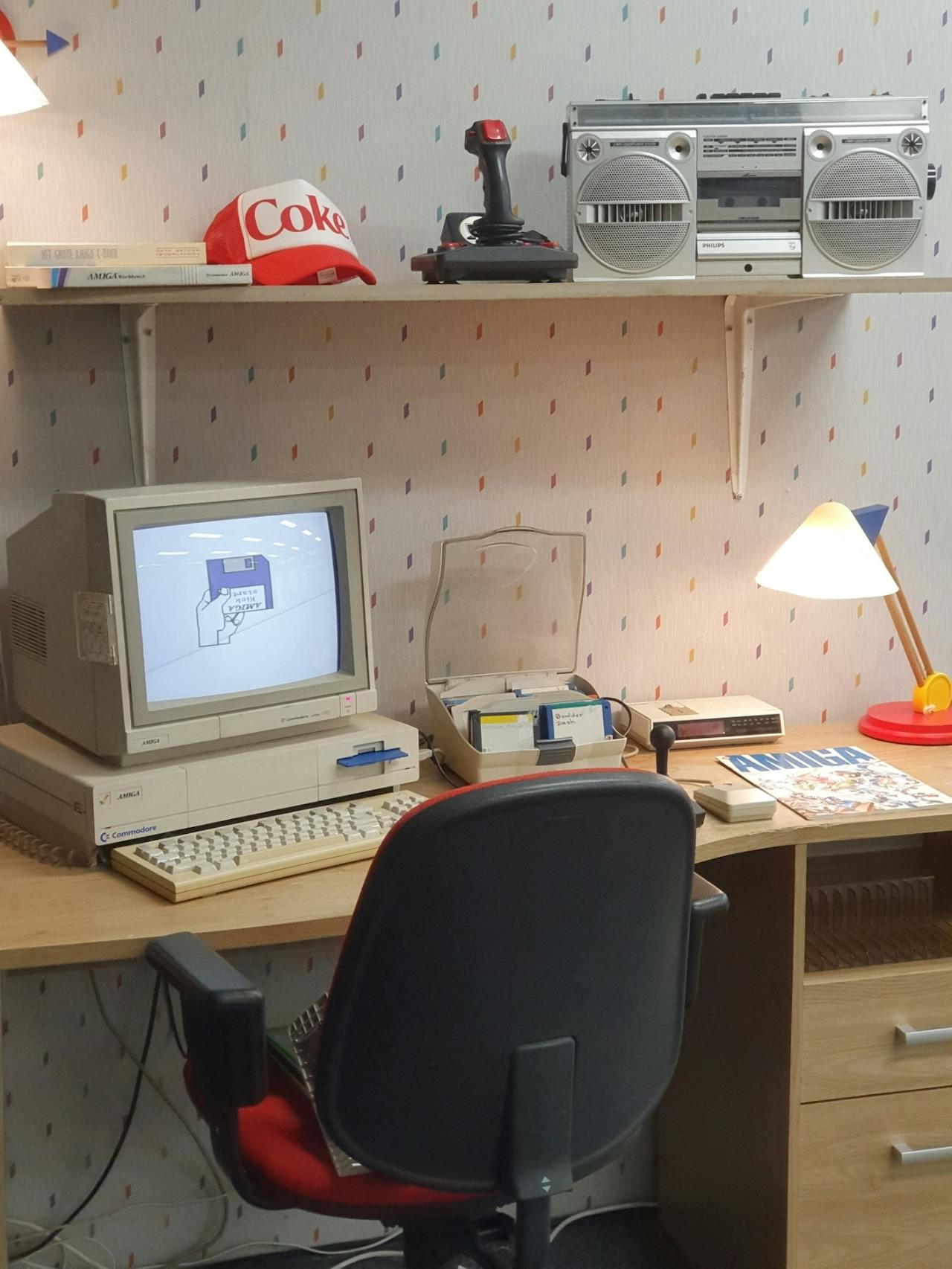 Een houten bureau met een ouderwetse computer en floppy-disks erop.