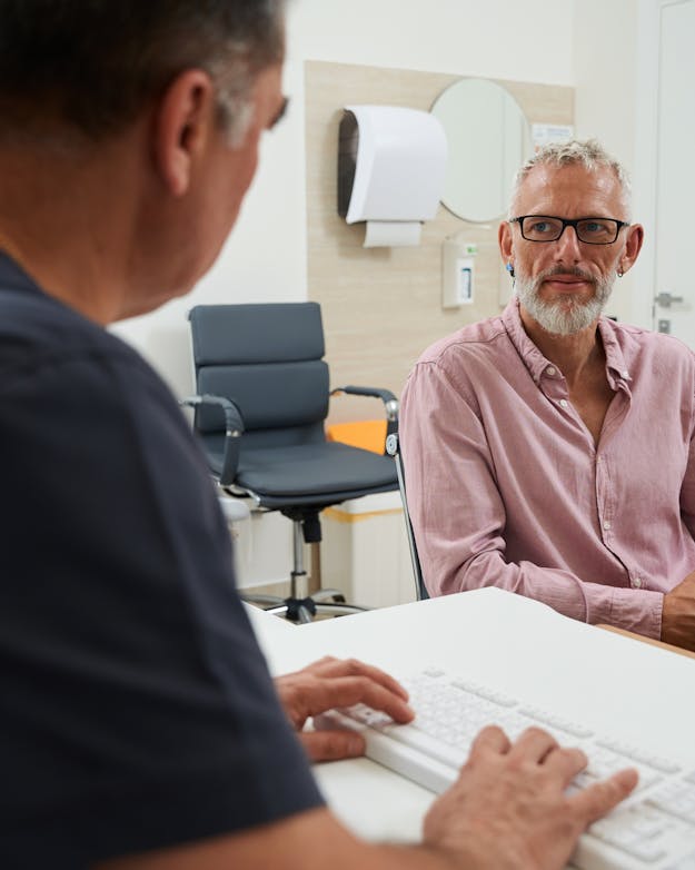 Je onderlinge relatie - broer/zus, arts/patiënt - bepaalt mede hoe je onjuiste opvattingen het beste kunt weerleggen. Spreekkamer van een mannelijke huisarts die in gesprek is met een patiënt, een oudere man.