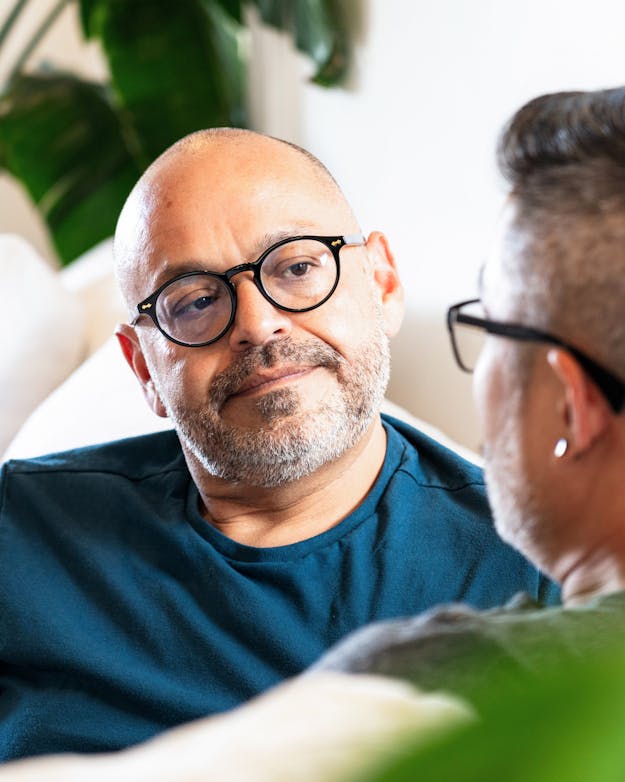 Wees in een gesprek oprecht nieuwsgierig Twee mensen op een witte bank, de man luistert naar de vrouw