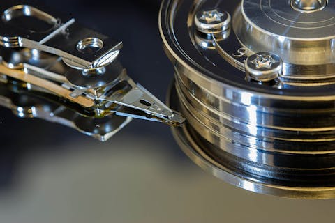 Detail van een harde schijf. Detail uit een harde schijf: een metalen cilinder met de punt van een metalen leeskop erbij.