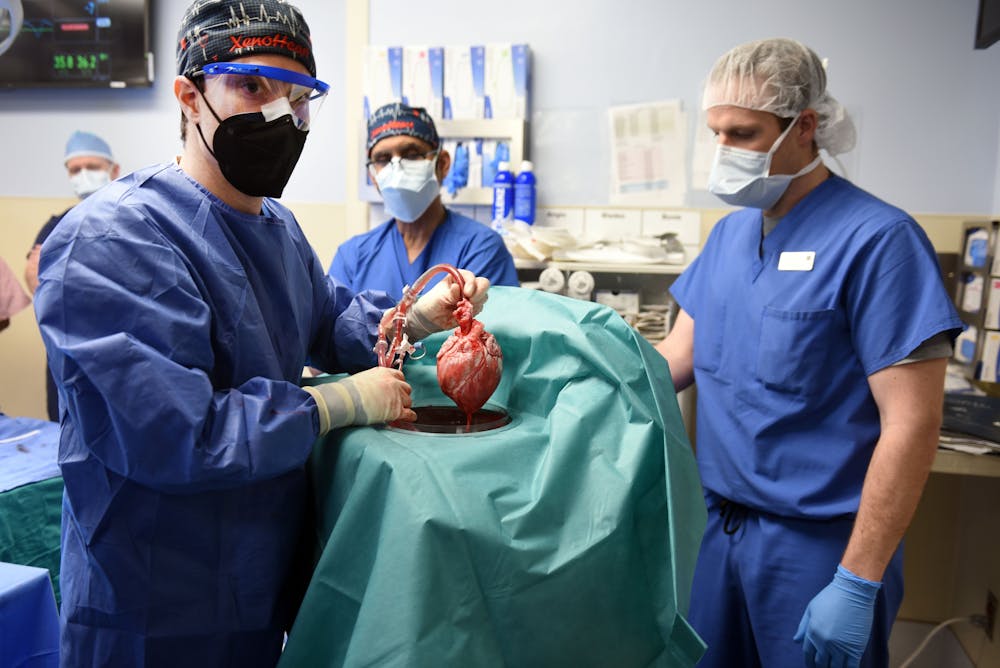 Een groep chirurgen in een operatiekamer. Zij houden een hart vast.