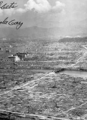 Een zwart-wit foto van Hiroshima, na de atoombom. Op de foto is een handschrift van de piloot Paul Tibbets te lezen.