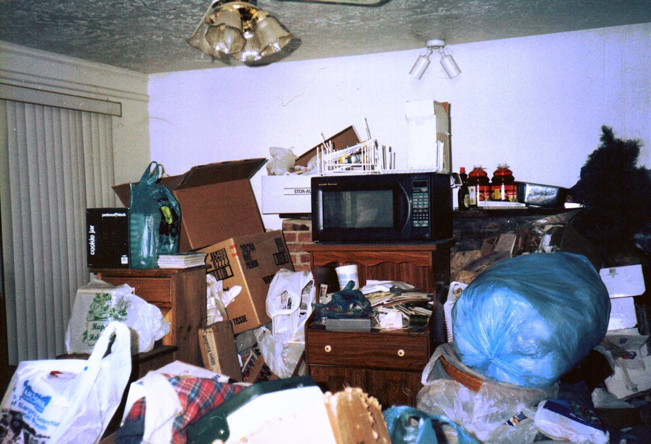 Een kamer gevuld met veel rommel hoog opgestapeld in de kamer.