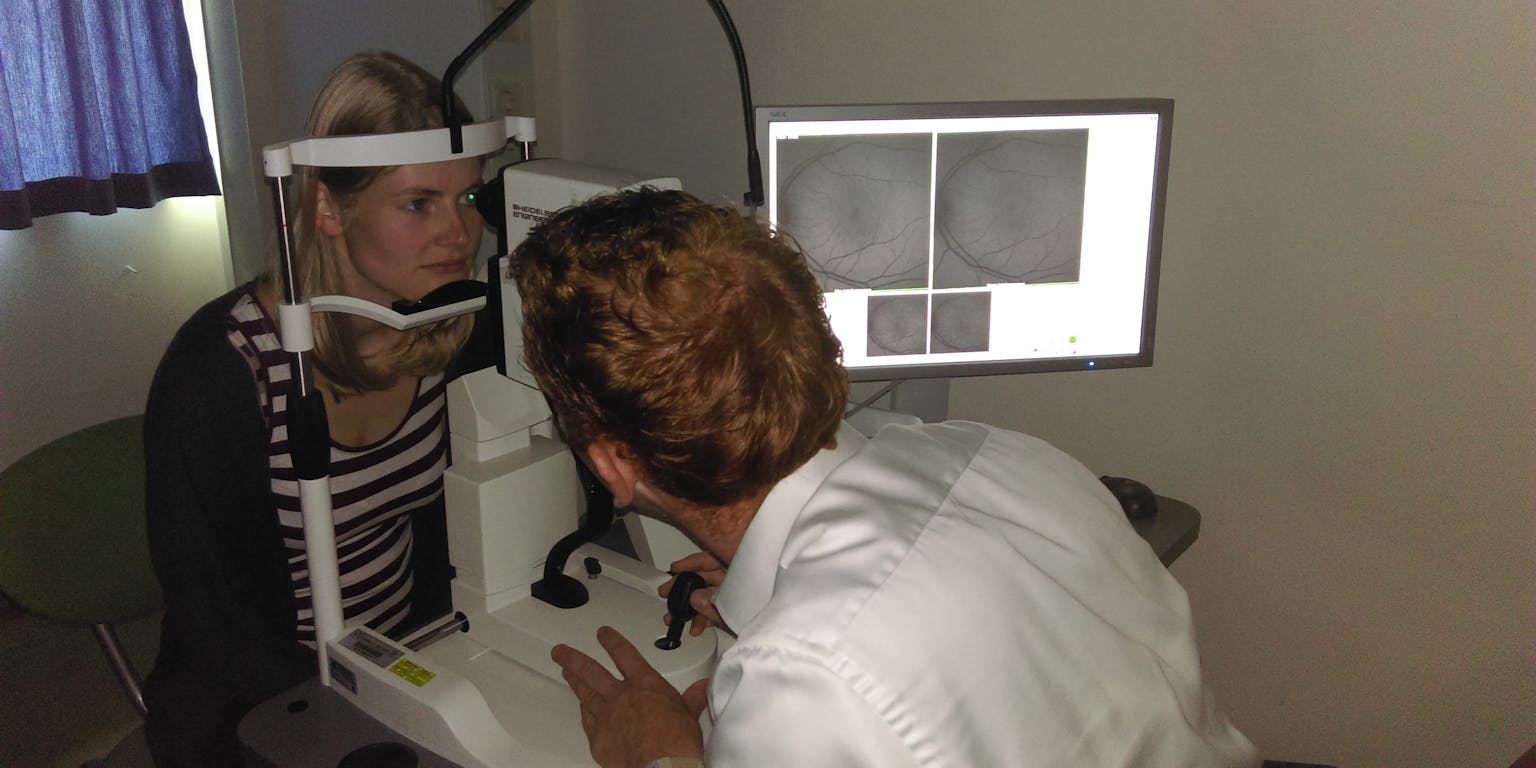 Een arts maakt een oogscan bij een patiënt.