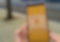 Een persoon die een smartphone vasthoudt met een geel vergrendelscherm.