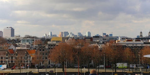 Skyline van Amsterdam, met op de voorgrond een rij oude panden en op de achtergrond moderne hoogbouw.