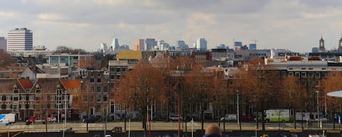 Het uitzicht vanaf het dak van NEMO Science Museum, met op de voorgrond oude panden en op de achtergrond moderne hoogbouw. Skyline van Amsterdam, met op de voorgrond een rij oude panden en op de achtergrond moderne hoogbouw.
