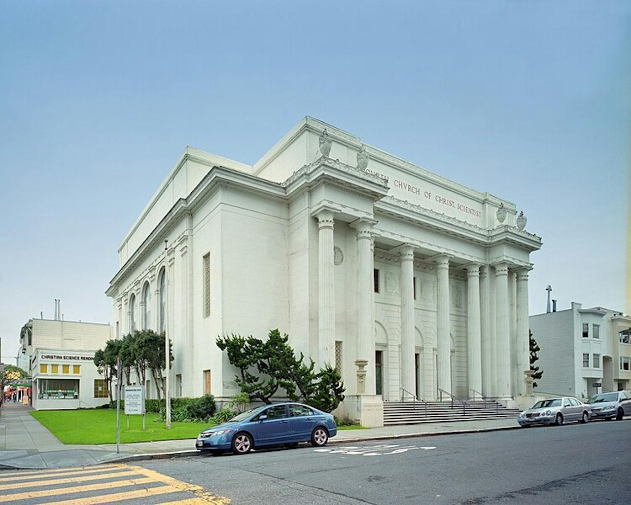 Een groot, wit, oud gebouw met zuilen aan de voorkant aan een Amerikaanse straat.