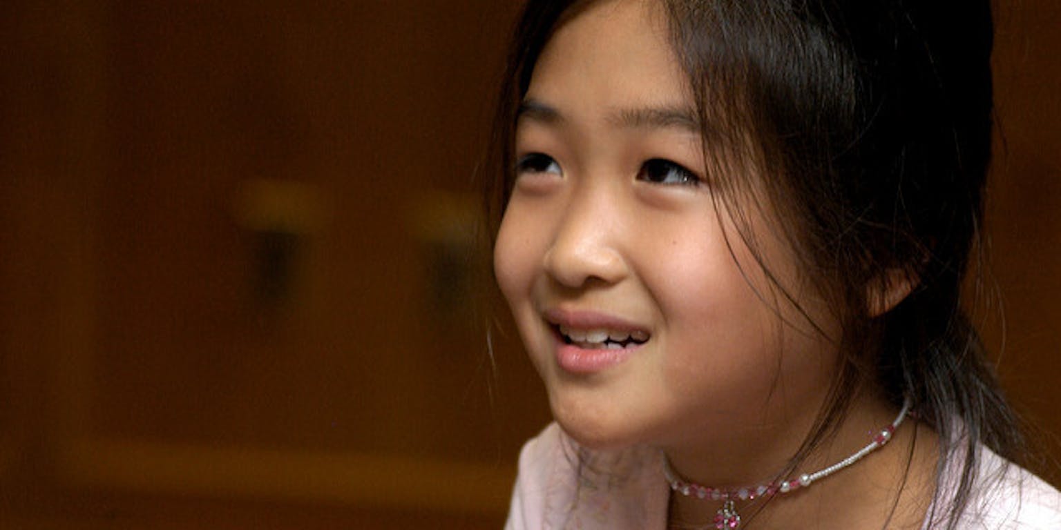 Een klein meisje kijkt dromerig voor zich uit.