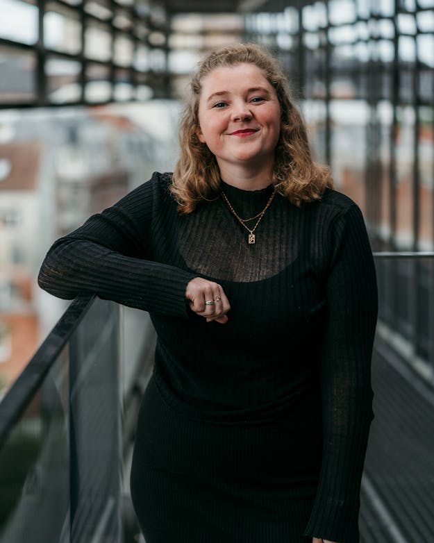 Janneke kijkt met een arm op een reling lachend de camera in. Janneke kijkt met een arm op een reling lachend de camera in.