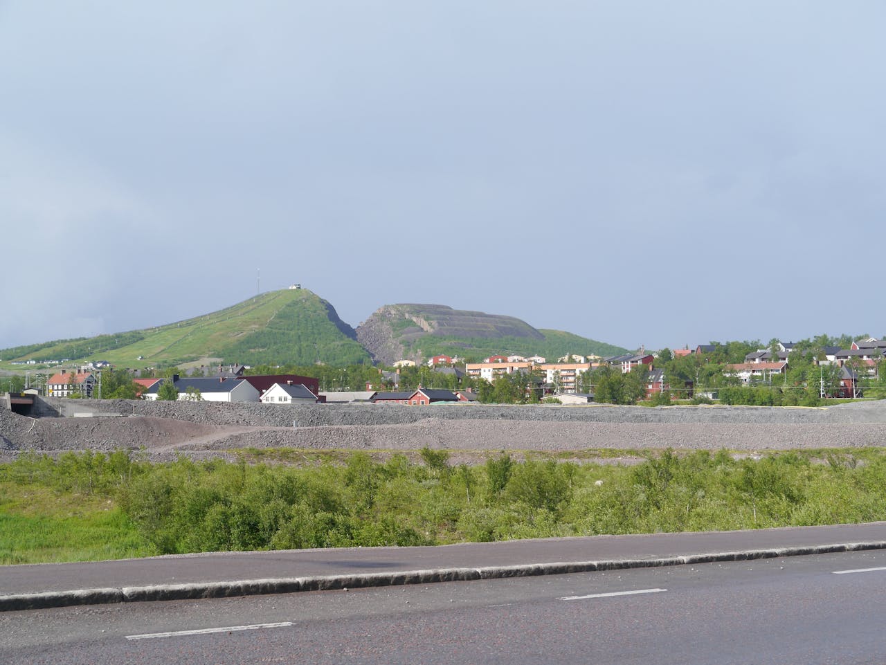 Een weg met een dorp en een heuvel op de achtergrond.