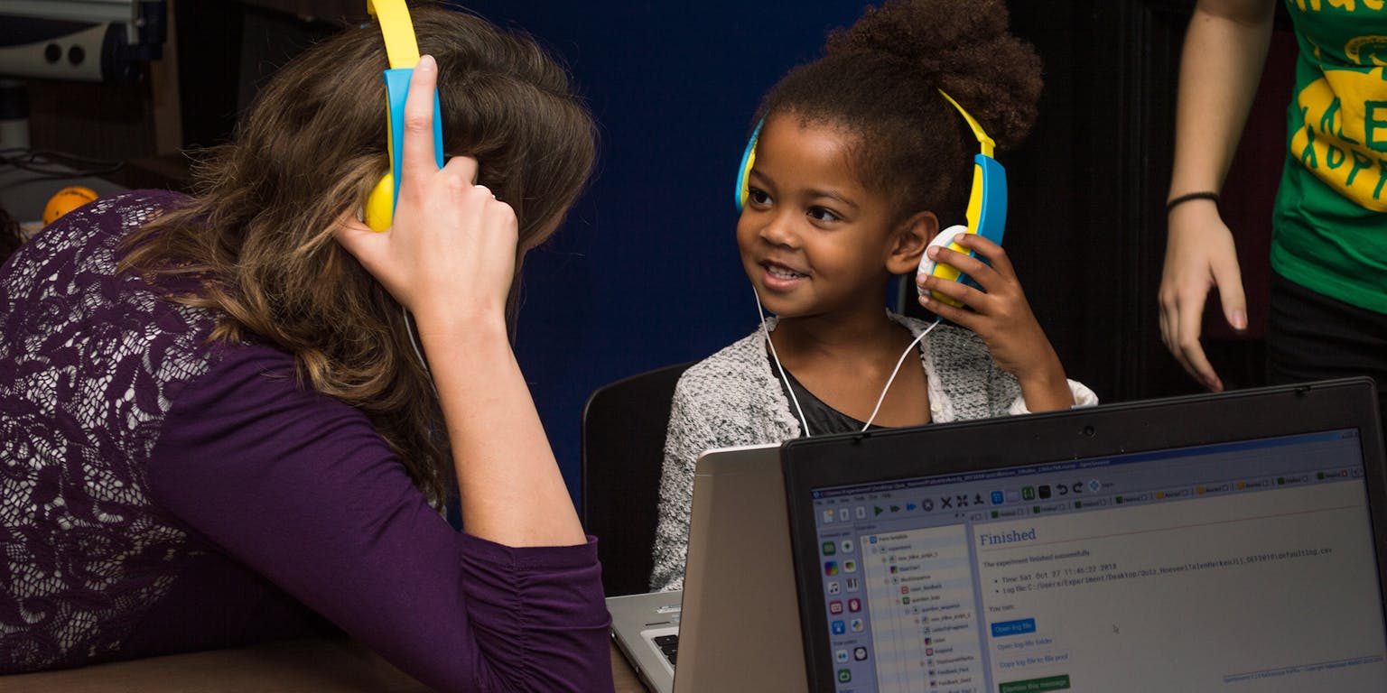 Een vrouw en een kind met dezelfde koptelefoon op.