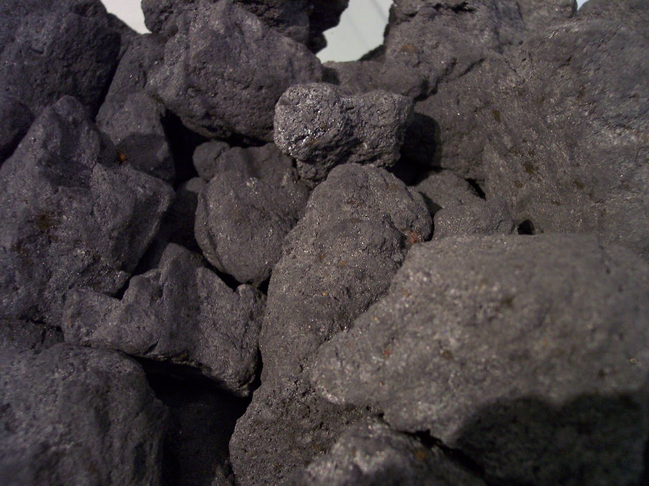Een stapel cokes die eruit zien als zwarte stenen op een witte achtergrond