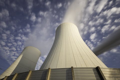 In Duitsland nemen kolencentrales, zoals deze op bruinkool gestookte centrale Schkopau, zo’n 25 procent van de elektriciteitsproductie voor hun rekening. Twee koeltorens van onderaf gefotografeerd tegen een blauwe lucht met schapenwolkjes. Uit de beide torens komt witte rook.