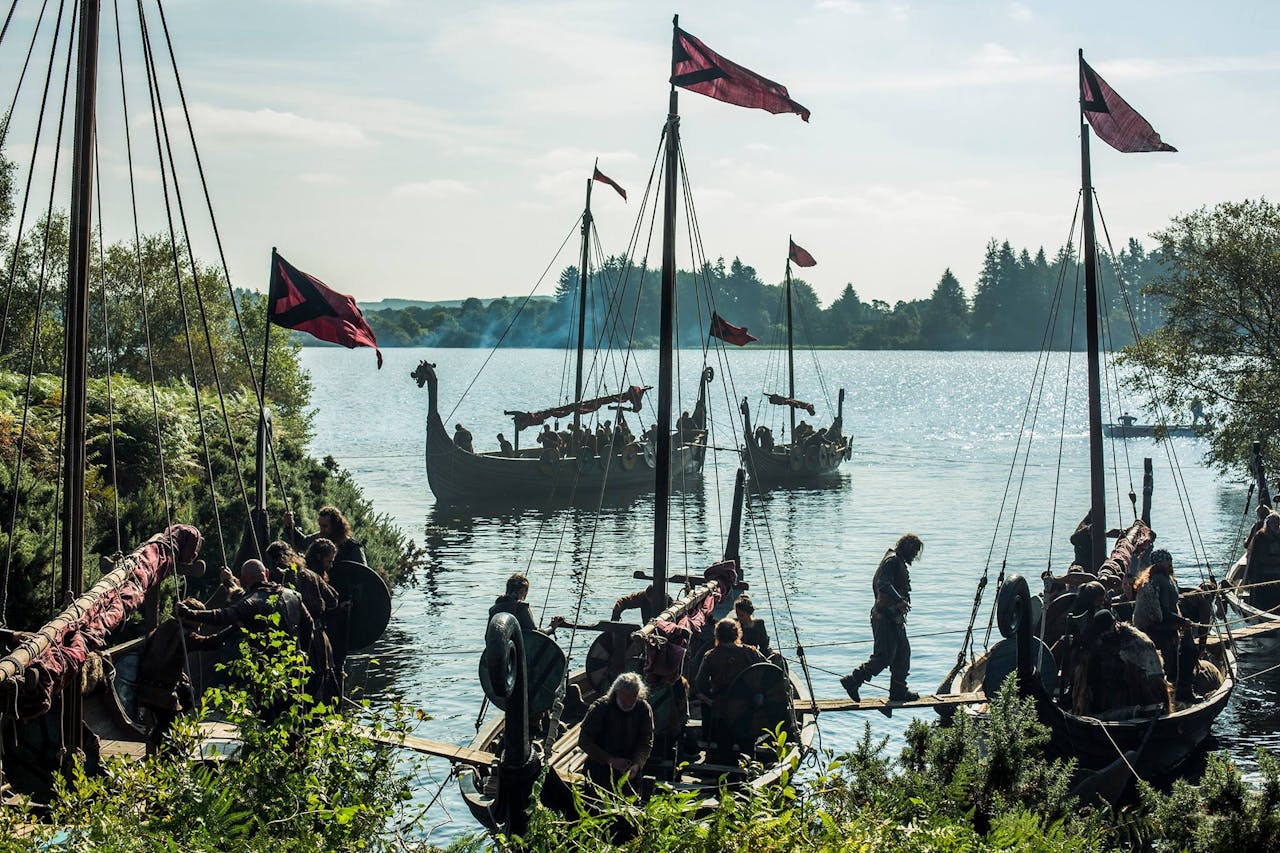 Vikingboten aangemeerd aan een meer met vlaggen.