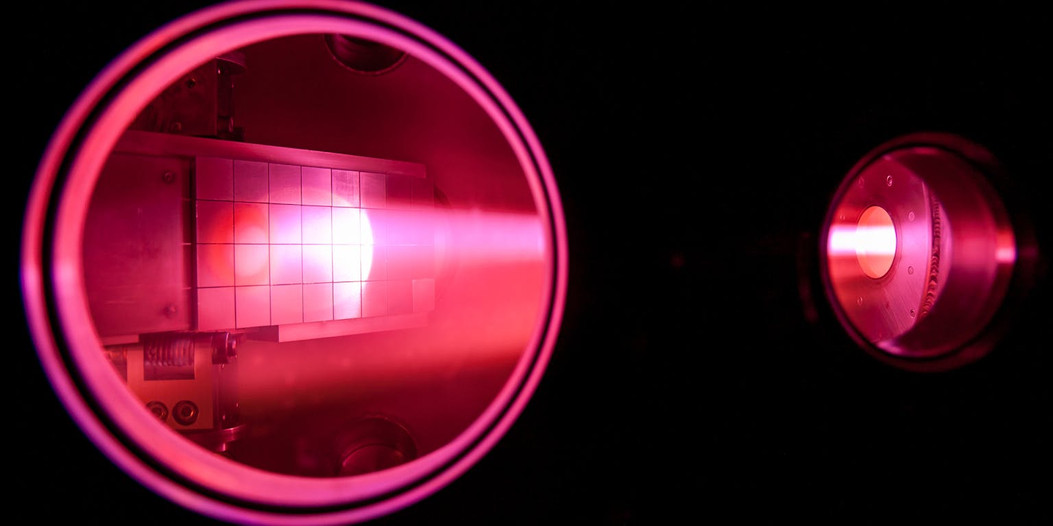 Een close-up van gemagnetiseerd plasma met roze licht in een donkere ruimte.