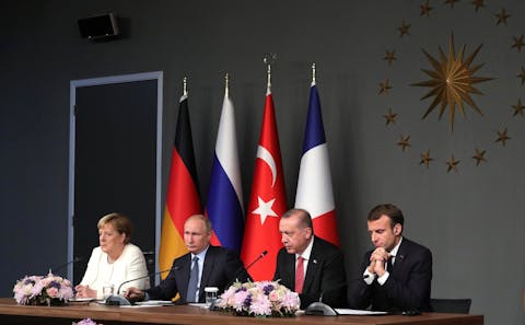 Een topontmoeting met Rusland in 2021 had volgens Merkel een verdere escalatie van het conflict in Oekraïne kunnen voorkomen. Een lange tafel waar, van links naar rechts, Angela Merkel, Vladimir Poetin, Recep Erdoğan en Emmanuel Macron naast elkaar zitten. Zij geven een gezamenlijke persconferentie.