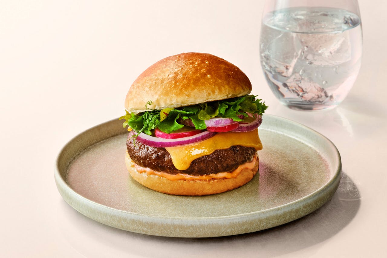Geef nou toe: hij ziet er best smakelijk uit, die kweekburger van Mosa Meat. Foto van Mosaburger van runderkweekvlees, met broodje, kaas, ui en sla.