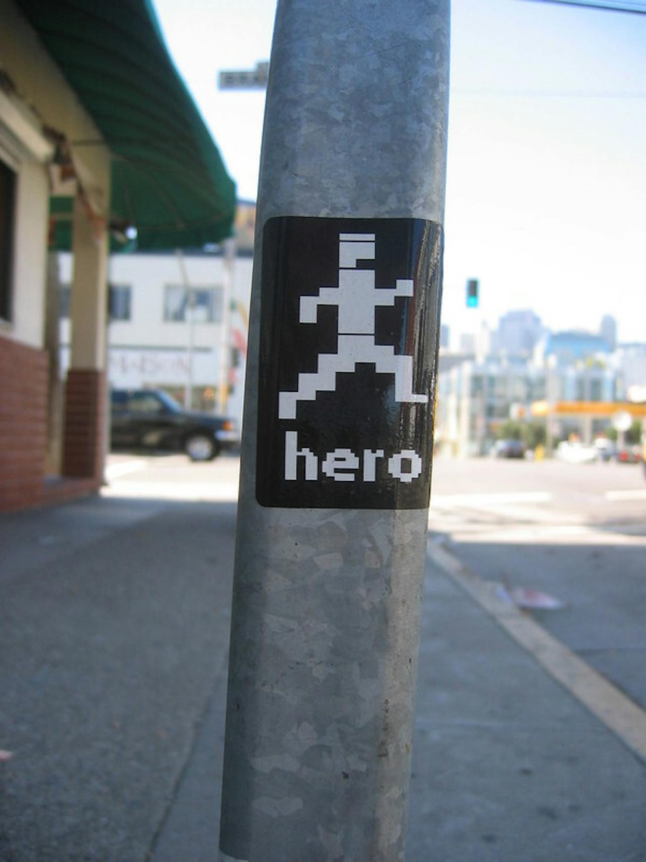 Een close-up van een lantaarnpaal met daarop een zwarte sticker met het woord held erop.