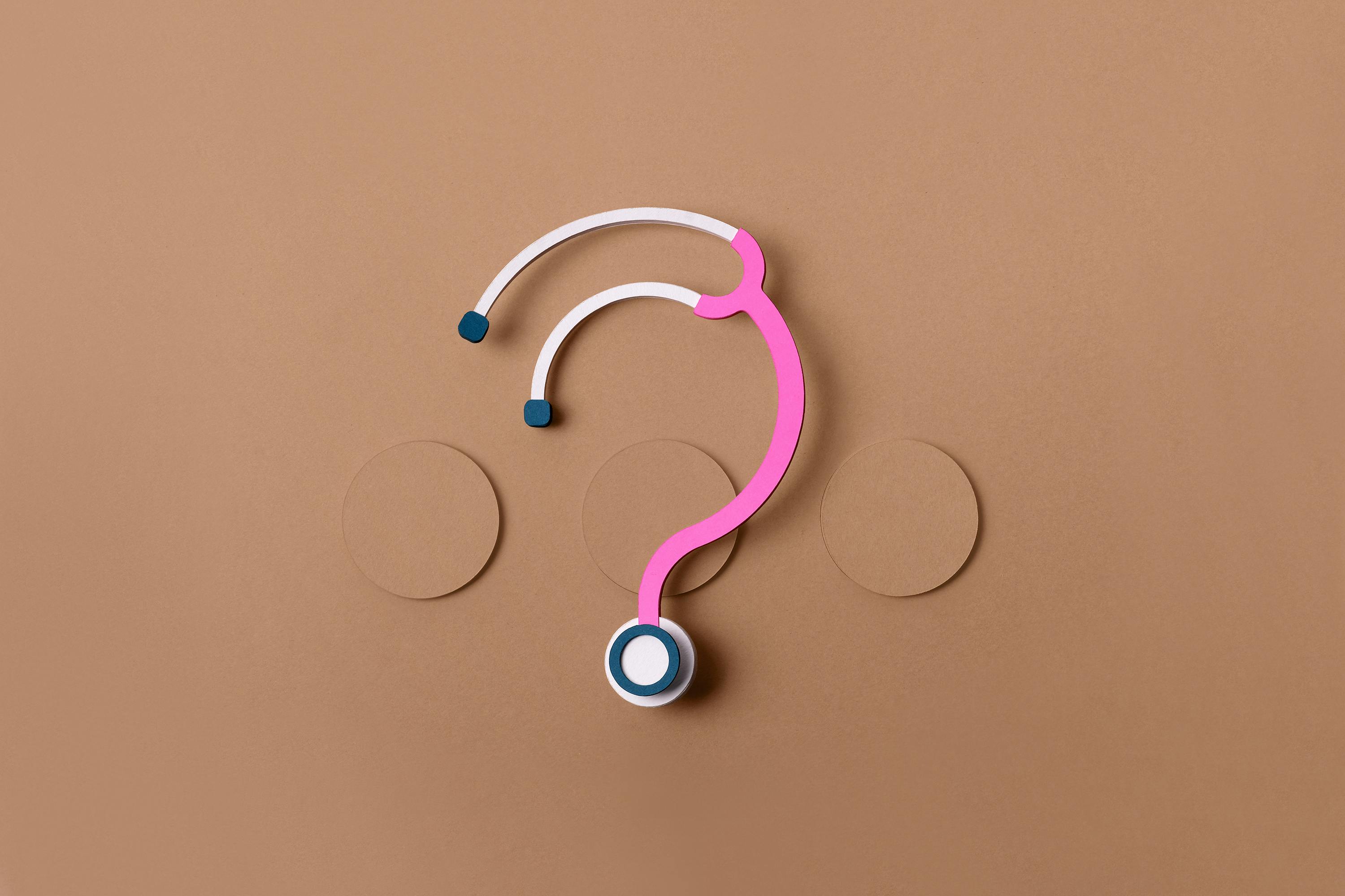 Roze stethoscoop in de vorm van een vraagteken op een bruine achtergrond