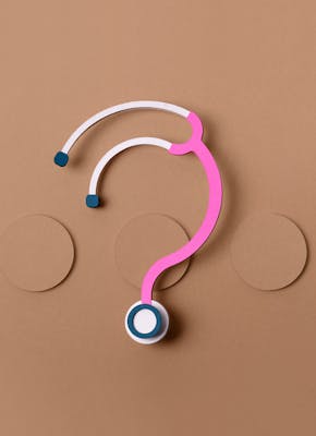 Roze stethoscoop in de vorm van een vraagteken op een bruine achtergrond