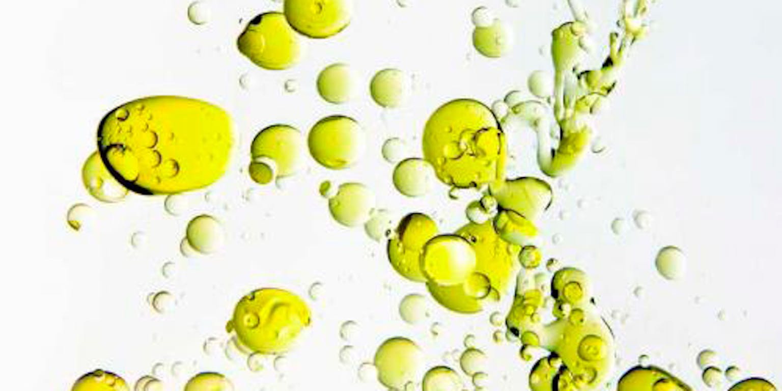 Olijfolie beweegt in de vorm van belletjes in water.
