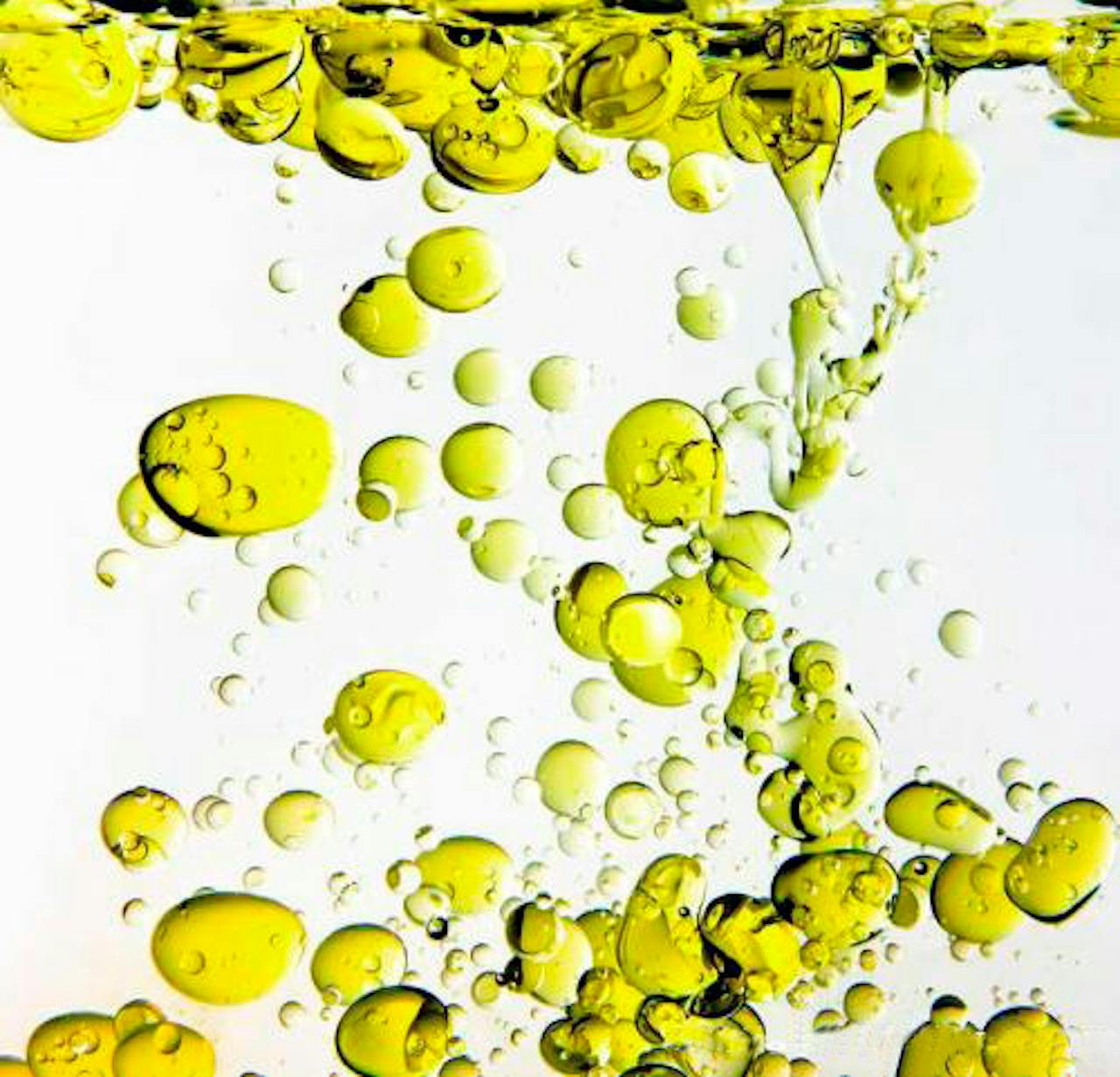 Olijfolie beweegt in de vorm van belletjes in water.