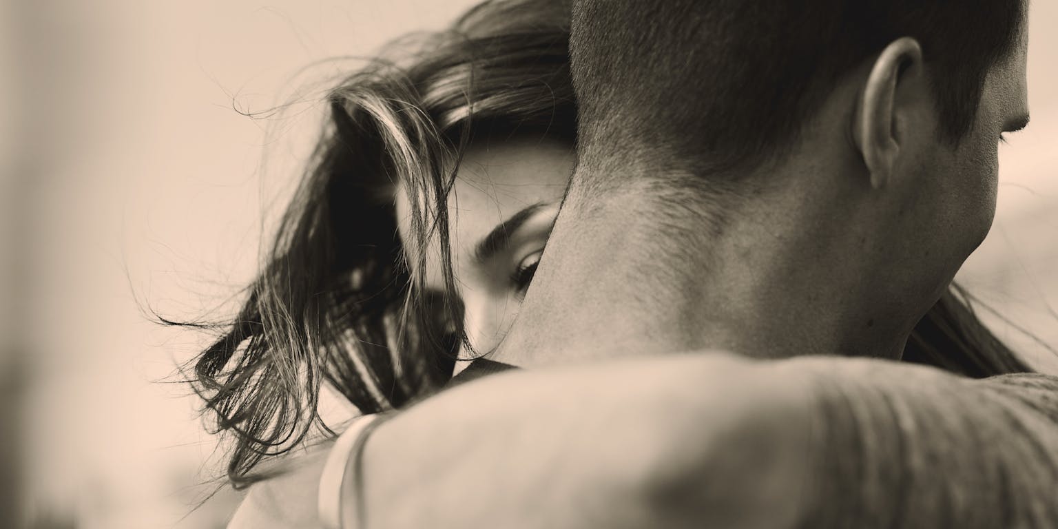 Een zwart-witfoto van een man die een vrouw omhelst.