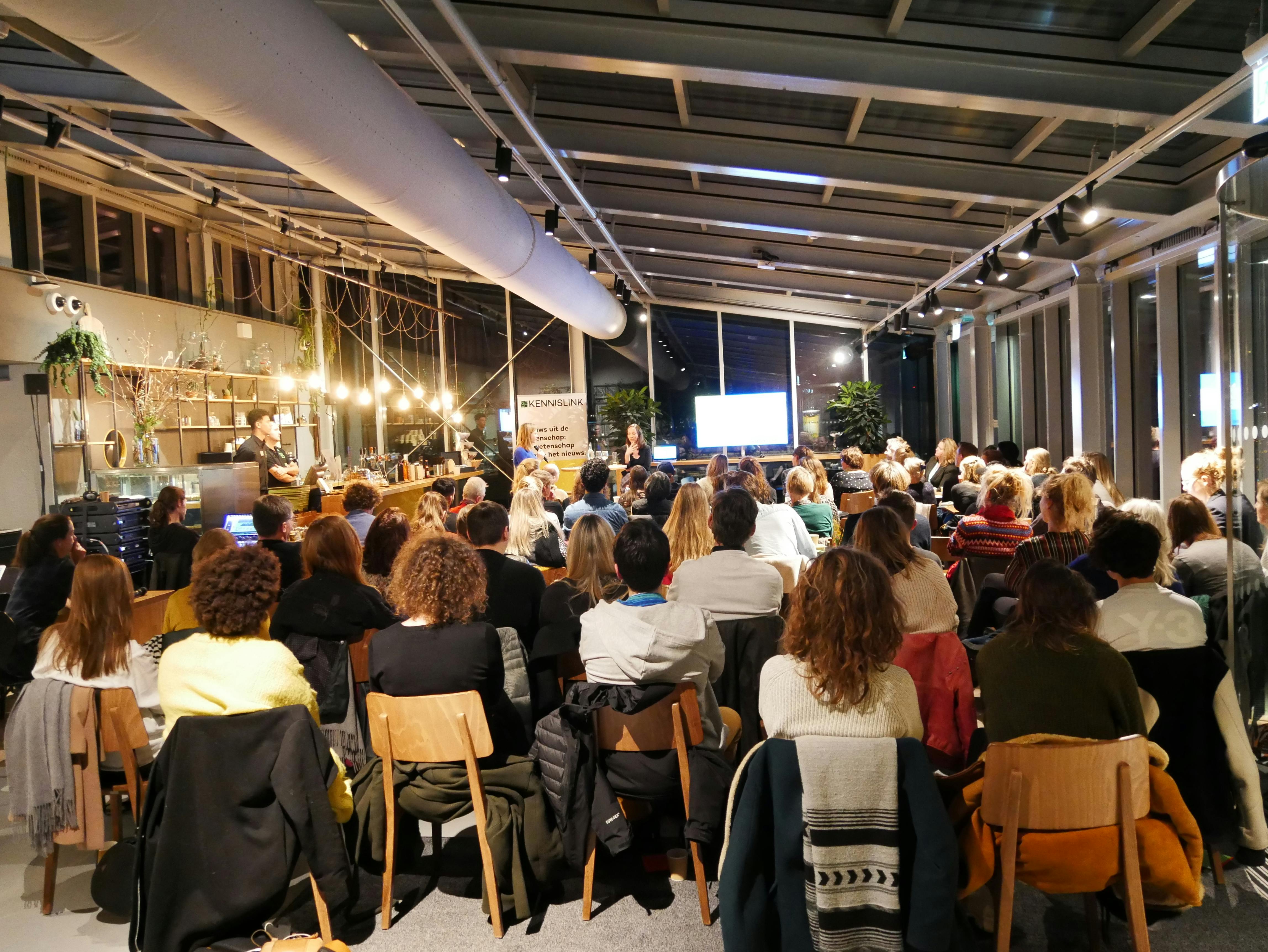 Een grote groep mensen tijdens een presentatie.