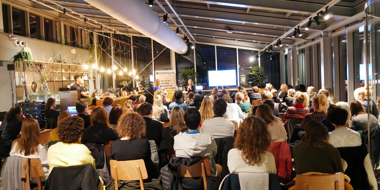 Een grote groep mensen tijdens een presentatie.