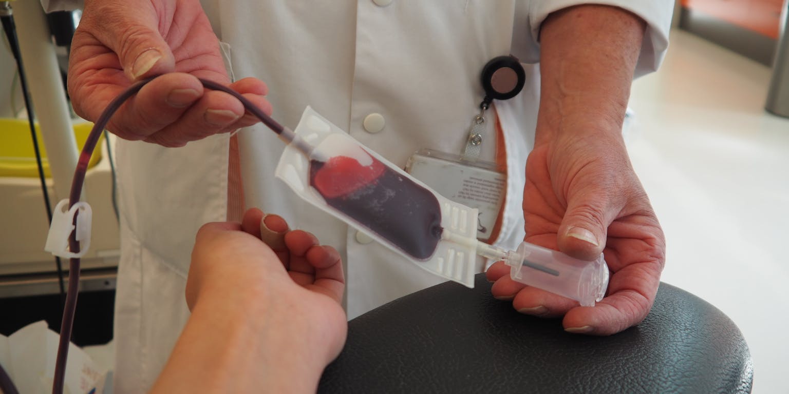 Een arts die een bloedmonster afneemt bij een bloeddonor.