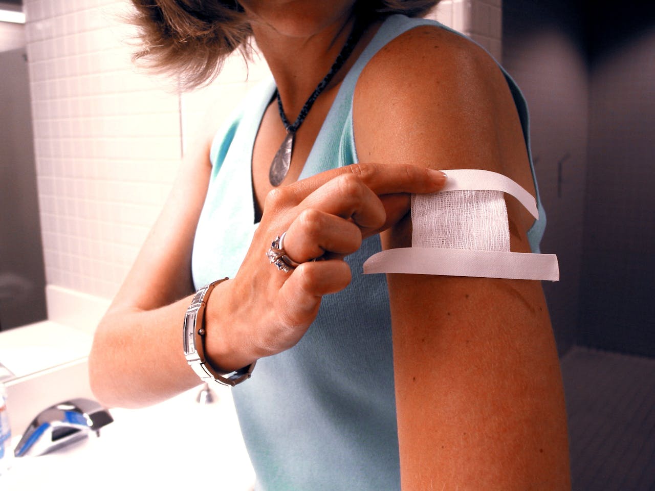 Een vrouw met een pleister op haar bovenarm. Ze heeft net een vaccinatie gehad.