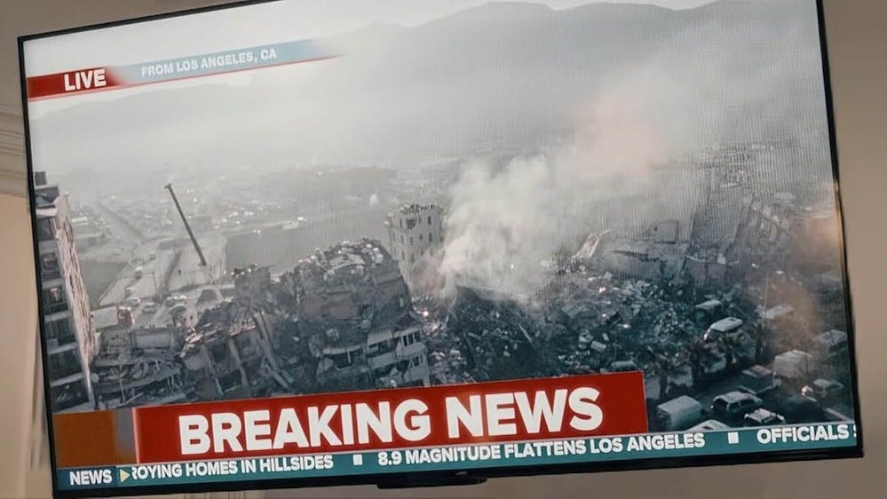 Een TV met daarop Breaking News en beelden van een stad die instort.