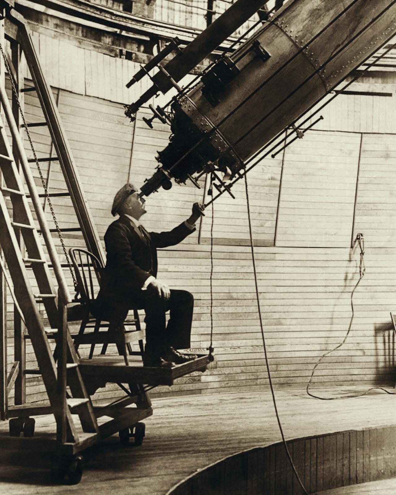 De Amerikaanse astronoom Percival Lowell kijkt door een telescoop in 1914.