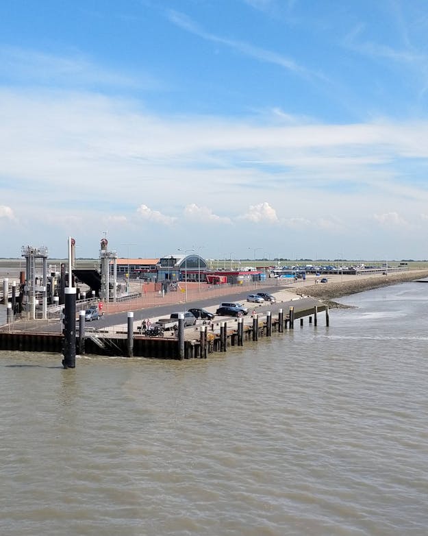 Pier Holwerd, gezien vanaf veerboot. Veerdienst naar en van Ameland door Wagenborg. Een veerdam ligt in troebel water. Er zijn geen schepen afgemeerd.