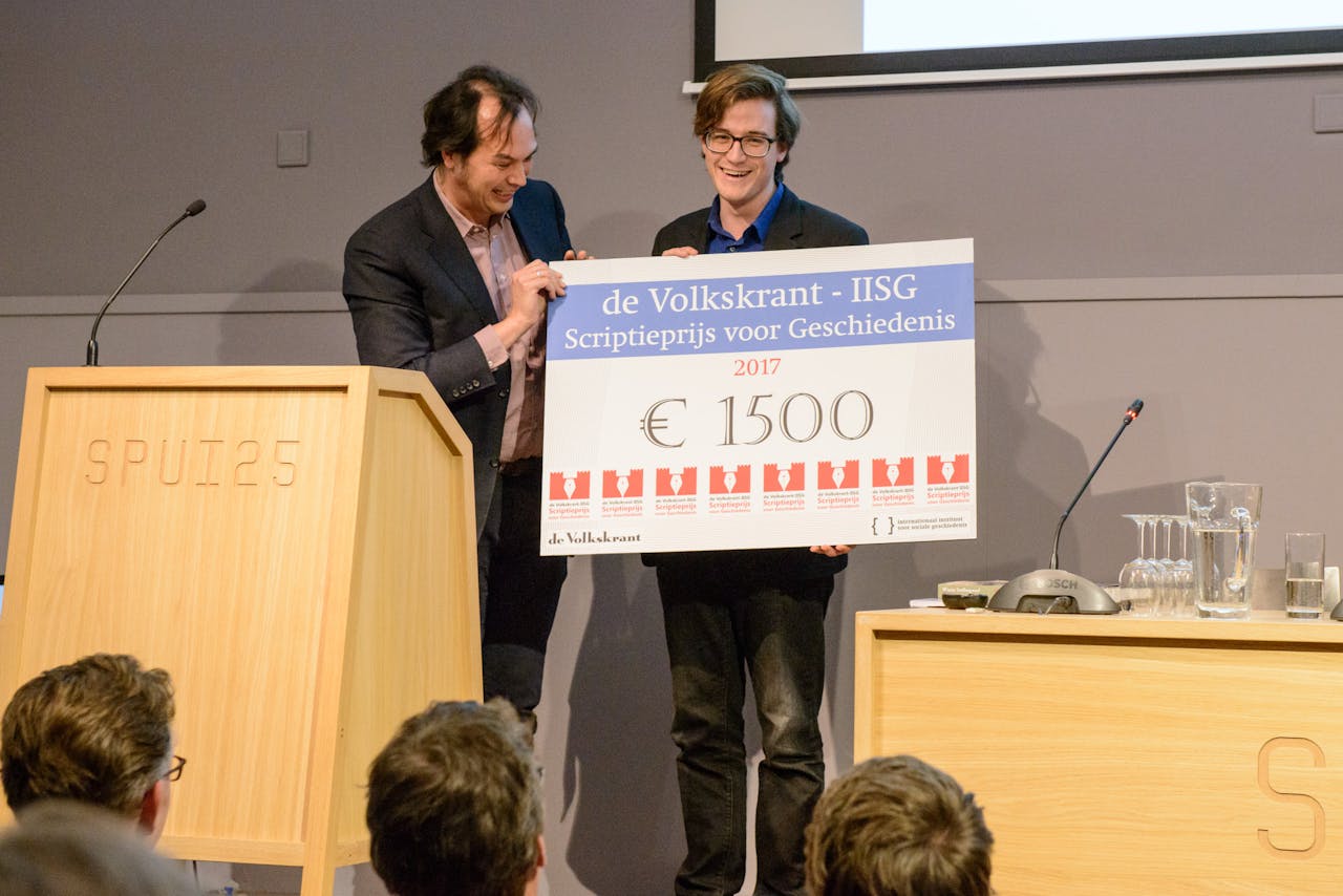 Olav Hofland wint de Volkskrant-IISG Scriptieprijs 2017. Juryvoorzitter Jouke Turpijn reikt de cheque van 1500 euro uit.