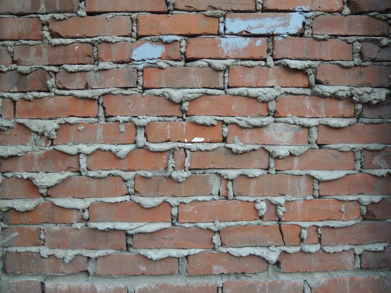 Een close-up van een rode bakstenen muur met grof cement.