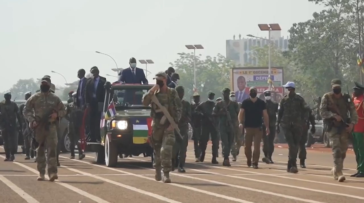 Russische beveiliging in Bangui loopt in legerkleding vooruit in stoet auto's