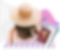 vrouw met hoed en paspoort van achteren gezien in vakantiestemming