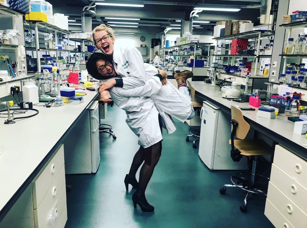 Werken met je vrienden maakt je werk zoveel leuker. Zij is één van mijn beste vriendinnen (Eline Sijbesma) vanaf mijn studententijd. Ze werkt in een andere onderzoeksgroep en werkt aan een totaal ander onderwerp dan ik, maar wij zien elkaar bijna dagelijks op het lab en bespreken samen de frustraties maar ook successen in onze projecten. Dan Jing Wu en Eline Sijbesma omhelzen elkaar in een laboratorium.
