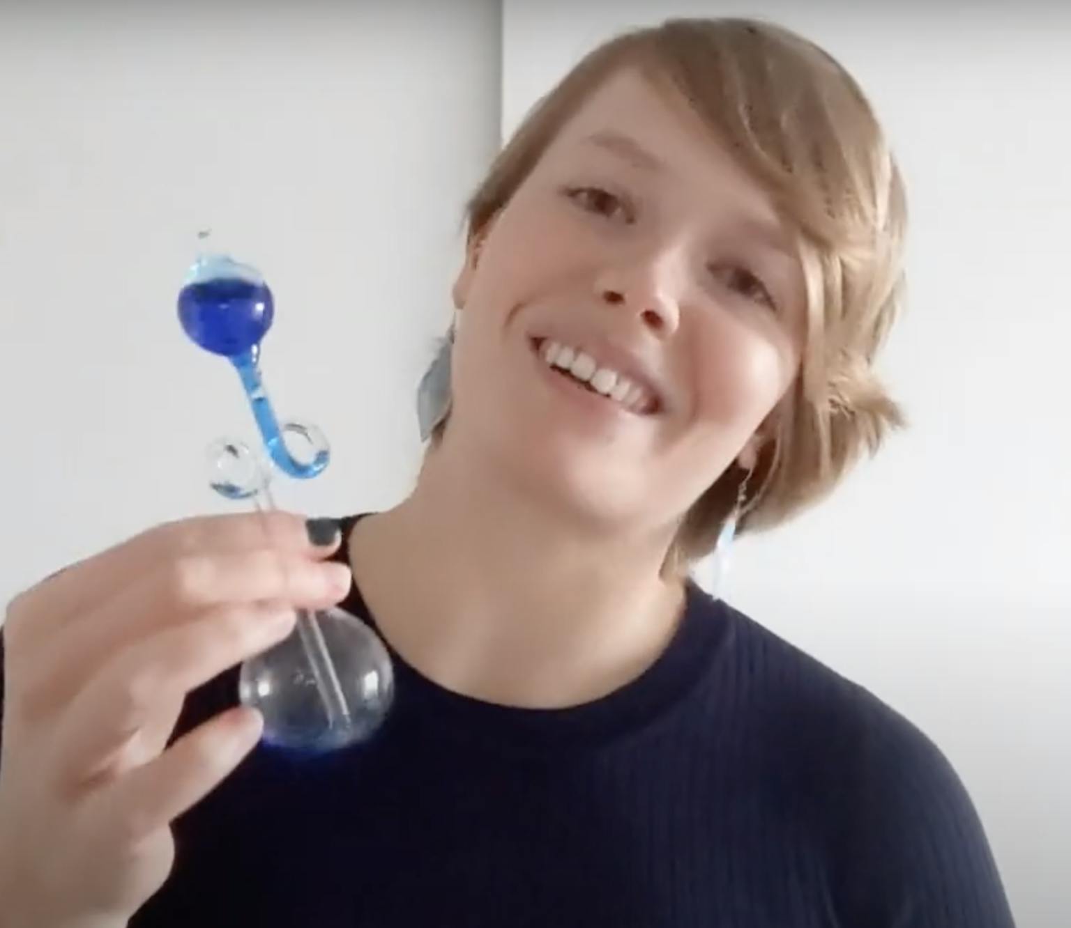 Een vrouw houdt een blauwe glazen fles in haar hand.