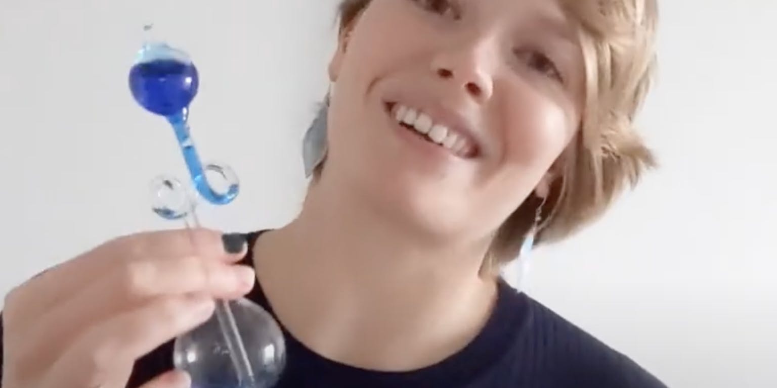 Een vrouw houdt een blauwe glazen fles in haar hand.