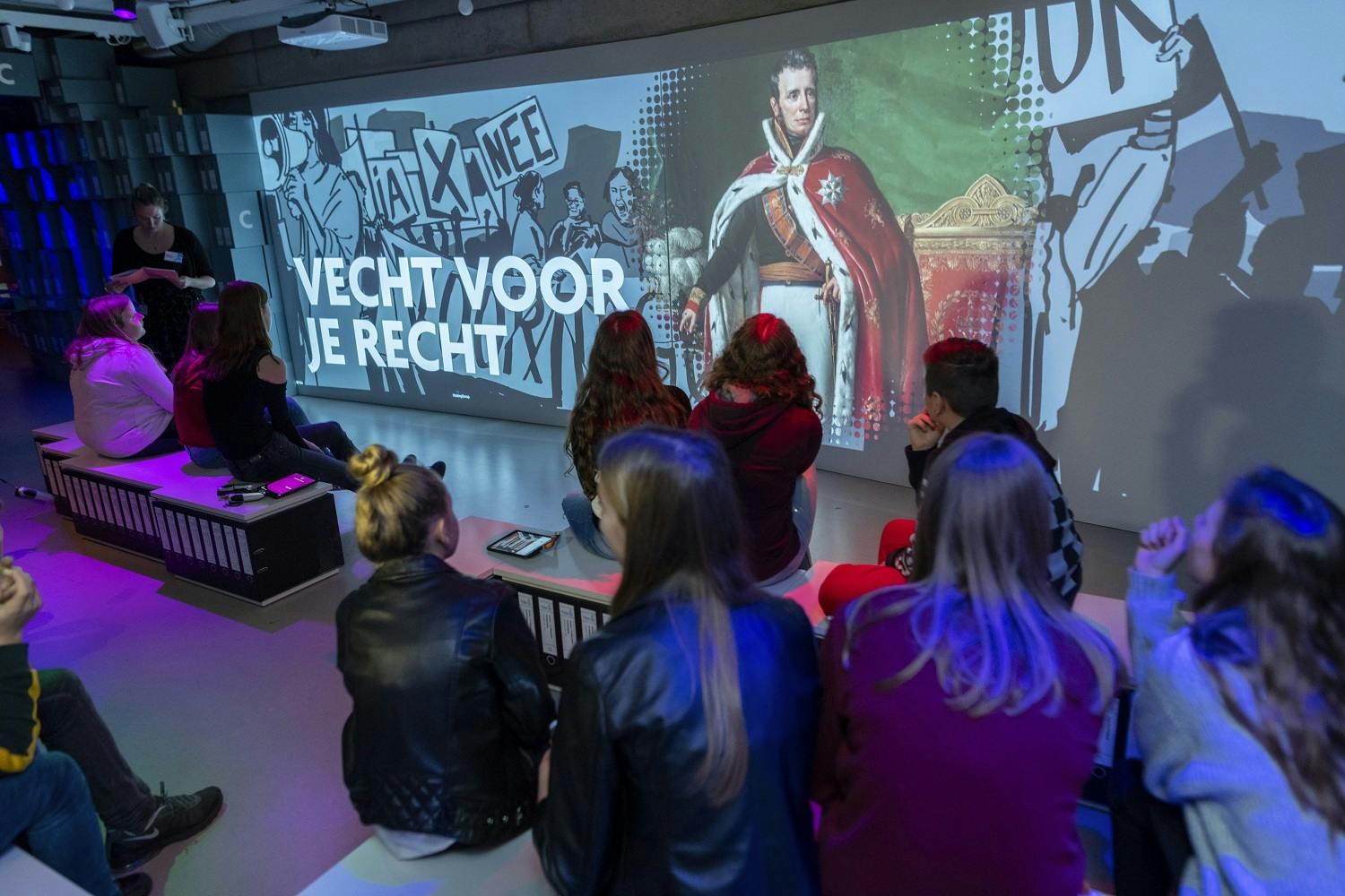 Een schoolklas kijkt naar 'Vecht voor je recht', een onderdeel van de tentoonstelling 'Wie ben ik, wie was jij?’ in het Nationaal Archief.