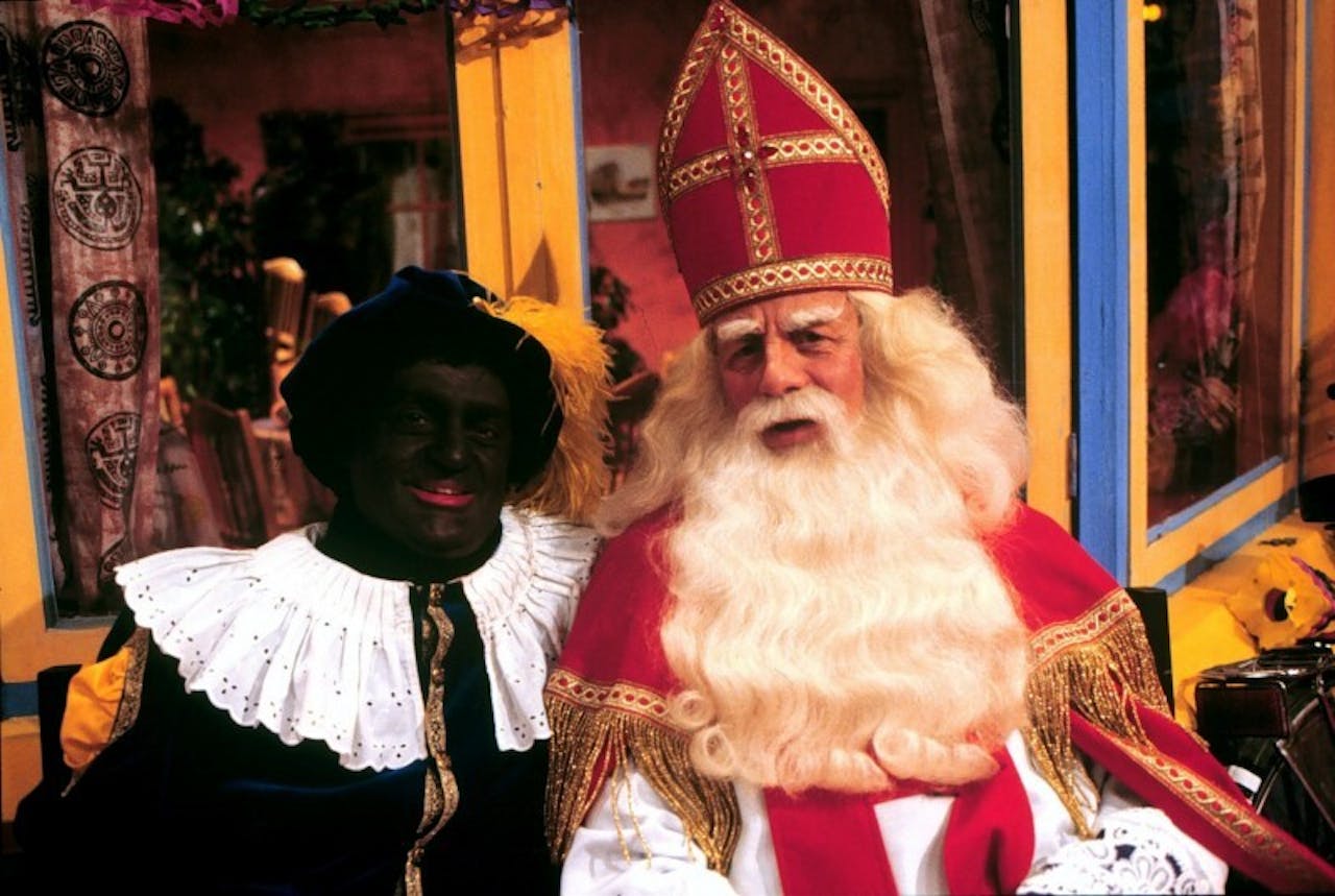 Een piet en sinterklaas poseren samen voor de camera.