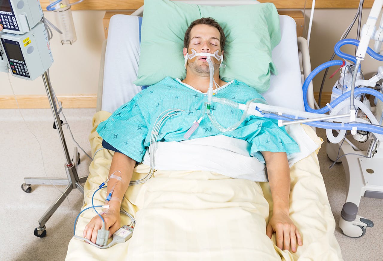Een man in een ziekenhuisbed die aan het infuus ligt.