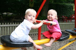Twee kleine kinderen spelen op een speelplaats.