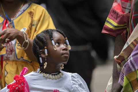 Het Sranantongo wordt binnen de Surinaamse gemeenschap weer steeds meer doorgegeven aan de nieuwe generaties. Meisje in traditionele Surinaams kleding kijkt schuin omhoog.