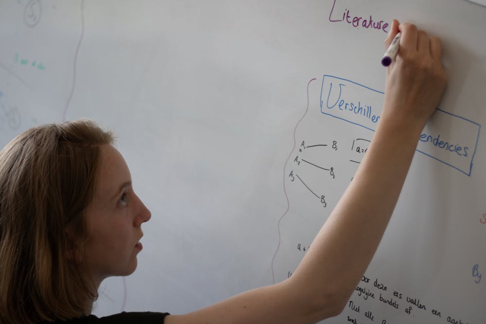 Tamara Florijn maakt een berekening met een marker op een white board